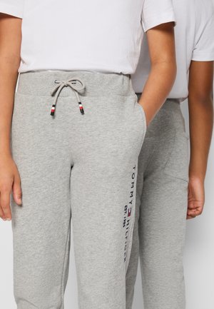 Graue Sweatpants aus weichem Material mit einem elastischen Bund, Kordelzug mit roten und blauen Akzenten und seitlichen Taschen mit einem Logo.
