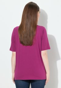 T-shirt violet à manches courtes avec une coupe décontractée, fabriqué en tissu lisse. Il présente un col rond et une finition propre visible à l'arrière.