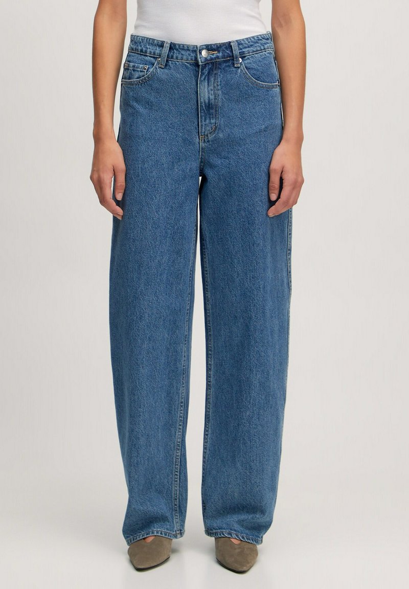 Jeans en denim bleus clairs à jambes larges, avec une taille haute, un design à cinq poches et une fermeture à bouton et éclair. Texture lisse.