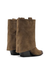 Stivali alla caviglia in suede marrone con un leggero tacco, caratterizzati da un design piegato e linguette di estrazione nella parte superiore. Texture liscia e suole nere robuste.