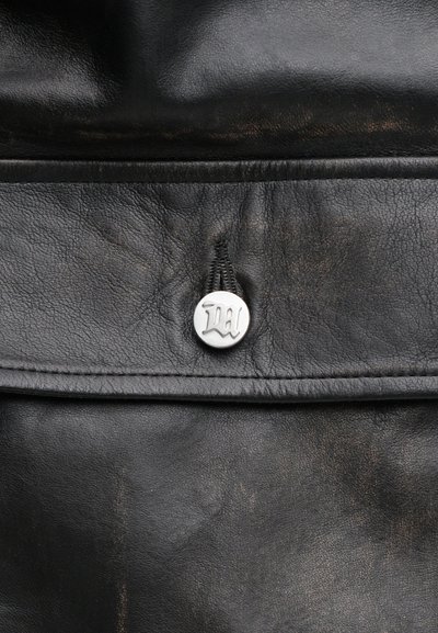 Sac en cuir noir avec une surface texturée, un design plié et un fermoir à pression en métal argenté avec des initiales "D." en relief.