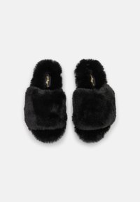 Black fur-lined slide slippers with a thick, soft upper and flat sole. Textured surface with a plush finish and minimalistic design.