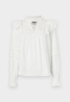 Balta garām piedurknēm blūze ar frillēm plecos, izgriezuma apkakli un dekoratīvām mežģīņu detaļām uz piedurknēm. Mīksts, viegls audums.