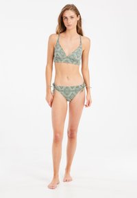 Grön mönstrad bikini med en triangulär bralette-topp och knytband i sidorna. Lättviktsmaterial med geometrisk design.
