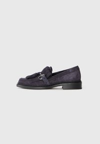 Loafer en velours violet foncé avec un détail de gland et une quincaillerie en ton argent, présentant un petit talon carré et une couture texturée autour de la semelle.