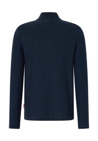 Tamsiai mėlynas ilgomis rankovėmis polo marškinėlis su mezginiu apykakle, ribinėmis rankogaliais ir mažu šoniniu logotipo ženkliuku. Minkšta tekstūra, klasikinis siluetas.