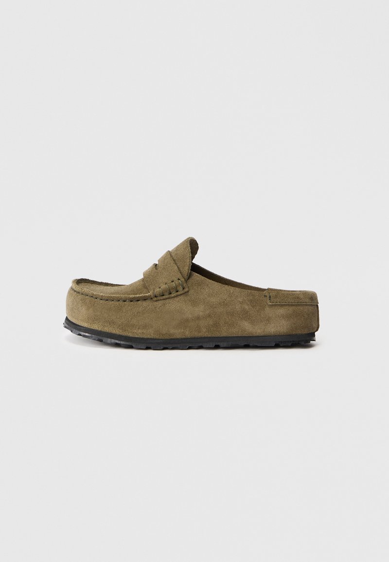 Olivgrüner Wildlederschuh zum Hineinschlüpfen mit Mokassin-Design, flacher schwarzer Gummisohle und dekorativer Naht oberhalb.