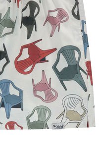 Tissu blanc avec des illustrations de chaises colorées en rouge, rose, vert, bleu et noir, présentant différents designs et orientations. Logo présent.