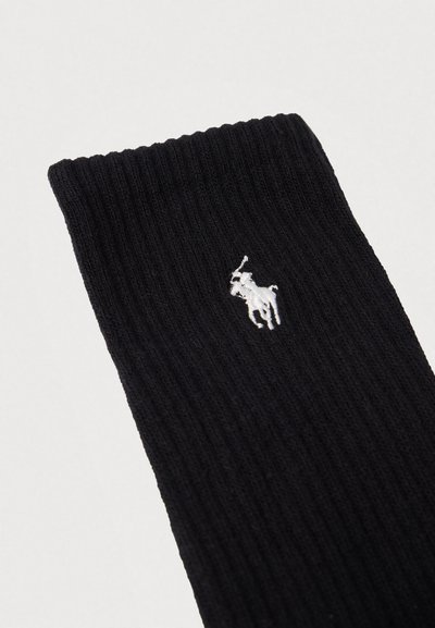 Fekete bordázott zokni fehér hímzett logóval. Az anyaga puha, a felső szélén texturált kivitelben.