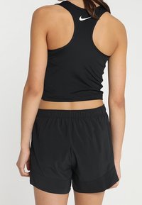 Czarny sportowy crop top o fasonie racerback, w komplecie z dopasowanymi czarnymi szortami sportowymi. Obie sztuki odzieży wykonane są z gładkiego materiału i mają minimalne zdobienia.