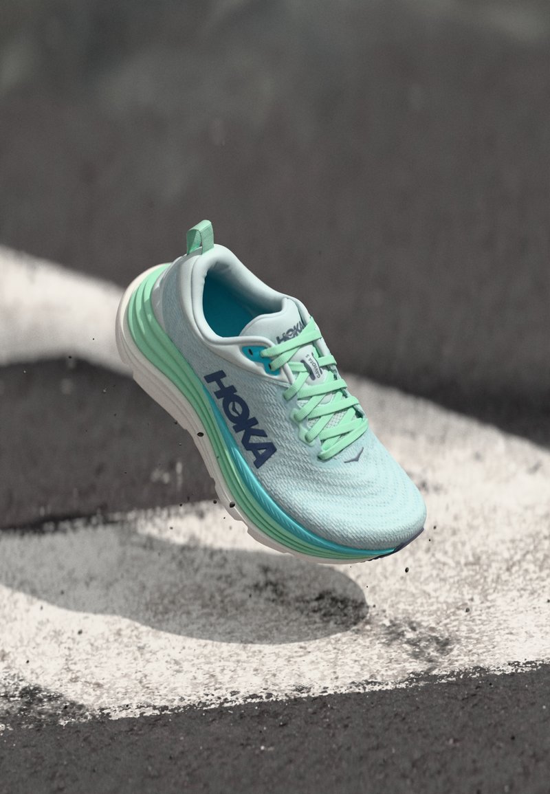 Light blue running shoe with a textured upper, green accents, and white sole. Features laces and a heel tab for easy wear.