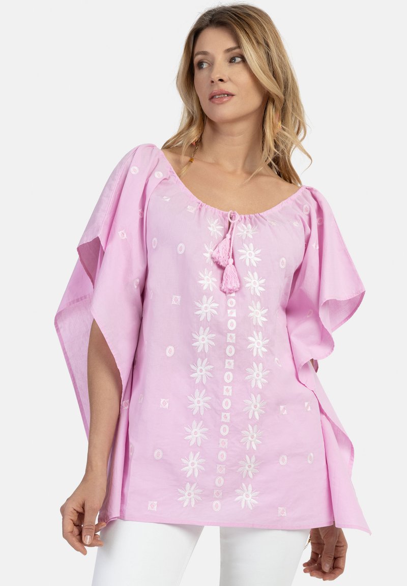 Lyserød bomulds-tunika med broderede blomster- og geometriske mønstre, store ærmer og en frynsebindning ved halsen.