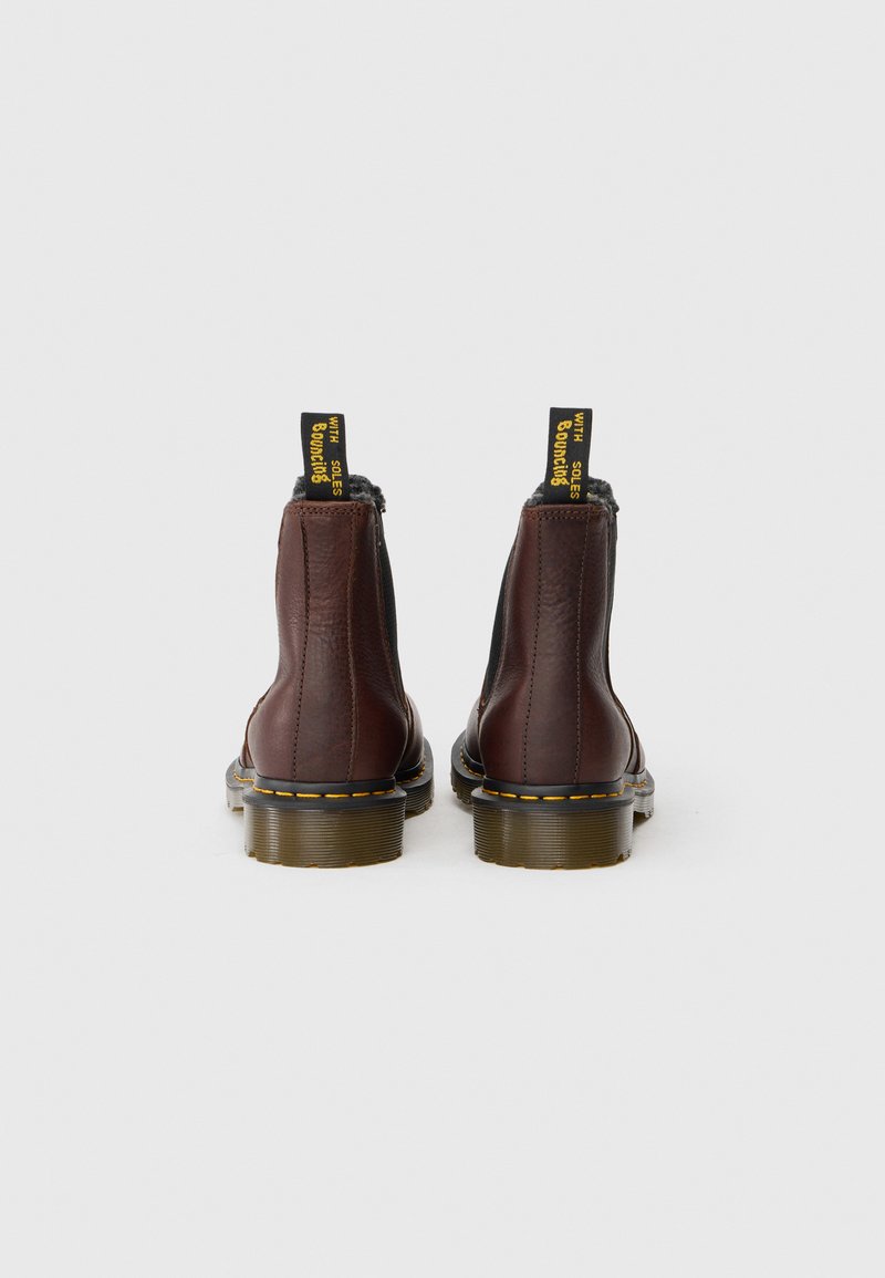 Braune Leder Chelsea-Stiefel mit elastischen Seitenteilen, gelben Nähten und schwarzen Gummisohlen. Schwarze Ziehschlaufen mit gelber Schrift auf der Rückseite.