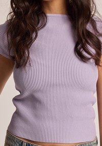 Levandulový pletený top s krátkými rukávy, kulatým výstřihem a přiléhavým střihem; textura je měkká a elastická, což zvyšuje pohodlí.