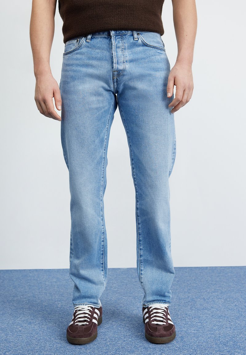 Jeans din denim de un albastru deschis, cu croială dreaptă, cinci buzunare �și un finisaj decolorat. Purtați cu adidași negri cu dungi albe.