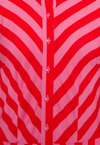 Czerwono-różowa, paskowana koszula button-up z wzorem w zygzak, z okrągłymi guzikami i miękką teksturą materiału.
