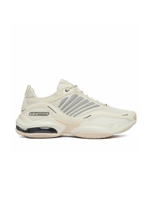 Beżowy sportowy sneaker Reebok z siateczkowymi panelami bocznymi, sznurowanym zapięciem, amortyzowaną podeszwą i widoczną poduszką powietrzną w okolicy pięty.