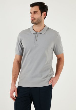 Grå kortærmet polo shirt med krave, tre-knaps placket og struktureret stof. Sammen med mørkeblå bukser.