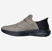 Schuh aus hellgrauem Wildleder mit einem schwarzen strukturierten Rückenteil, versehen mit Perforationen an der Seite, einer glatten, abgerundeten Spitze und einer gepolsterten Sohle.