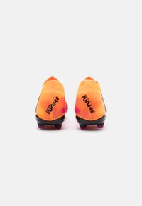 Scarpe da calcio di un vivace arancione con sfumature degradé e dettagli neri. Presentano una tomaia testurizzata, un tacco arrotondato e tacchetti con punta viola.