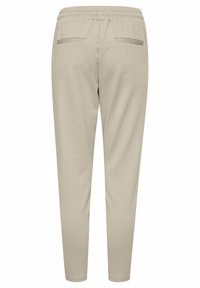 Ljusbeige joggers i mjukt tyg, med elastisk midja, två bakfickor och tapered ben. Slät textur med minimal detaljer.