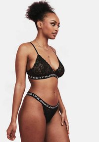 Zwart kanten bralette en slip set met een diepe halslijn, dunne bandjes en een tailleband met "DANDYFRANK" in het wit gedrukt.