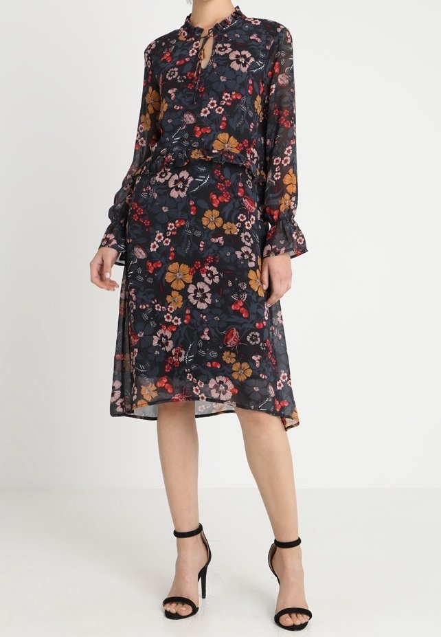 Robe imprimée florale en tissu transparent, avec un col montant, une ouverture en forme de goutte d'eau à l'avant, des manches longues et une silhouette évasée en ligne A. Fond bleu marine foncé.