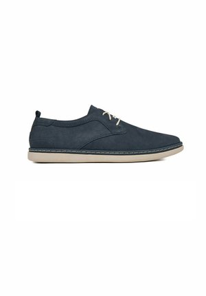 Zapato casual azul marino con cordones, suela beige y costura en contraste, diseño de perfil bajo y lengüeta trasera para tirar.