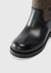 Stivale alla caviglia in pelle nera con punta arrotondata, caratterizzato da una tomaia in tessuto marrone a fantasia e una suola in gomma nera con cuciture visibili.
