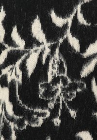 Schwarz-weiß gemusterter Strickstoff mit floralen Motiven; weiche Textur mit einem leichten Flaum und filigranen Blattdesigns.