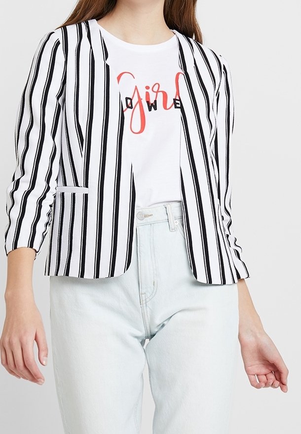 Czarny i biały marynarka w paski z dopasowanym krojem, klapami i dwiema przednimi kieszeniami, zestawiona z białym T-shirtem z grafiką oraz jasnymi dżinsami.