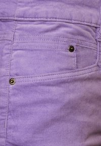 Paarse stof met een gladde textuur, voorzien van een voorzak en een metallic knoopaccent. Stikseldetails zijn zichtbaar langs de randen.