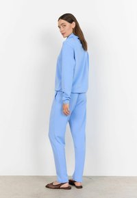 Lichtblauw loungewear set met een sweatshirt met hoge hals en bijpassende broek. Zachte stof, ontspannen pasvorm, met ribgebreide manchetten en zakken.