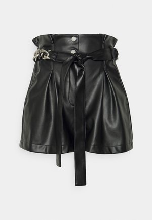 Minifalda negra de cuero sintético de talle alto con cintura paperbag, botones a presión frontales, cinturón atado y detalle de cadena plateada en un lado.