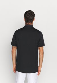 Svart polo skjorta, korta ärmar, blandat bomullsmaterial, enfärgad, klassisk krage, avslappnad passform, enkel baksida utan synlig branding eller mönster.