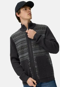 Grijze rits cardigan met ribgebreide mouwen, met een gestreepte voorkant in donker en licht grijs. Inclusief steekzakken en een hoge kraag.