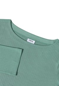 T-shirt vert clair à manches longues en côtelé avec un col rond et une étiquette de marque "CECIL" visible au niveau du col.