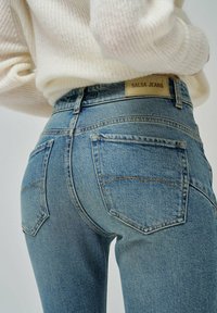 Jeans de mezclilla azul claro con cintura alta, costuras prominentes y dos bolsillos traseros. Etiqueta de la marca "SALSA JEANS" visible en la cinturilla.