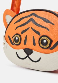 Oranssi tiikeri-muotoinen käsilaukku, jossa on teksturoitu nahka, mustat raidat, suuret pyöreät silmät ja kermaisen värinen pohja. Varustettu tukevalla hihnalla.