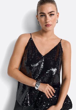 Svart paljettcamisole med tunna axelremmar, med en V-ringning. Matchas med en paljettclutch i samma stil och ett silverfärgat armband.