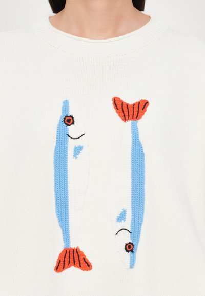 Witte gebreide trui met twee blauw en witte visontwerpen, met oranje accenten op de staarten en zwarte ogen, tegen een gestructureerde achtergrond.