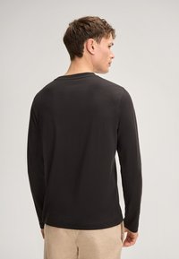 Schwarzes Langarmshirt aus weichem Stoff, mit Rundhalsausschnitt und einem einfachen, klaren Design ohne Muster oder Akzente.