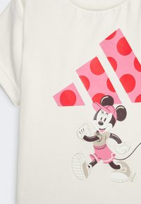 Weißes Baumwoll-T-Shirt mit einer Cartoon-Maus in einem pinken Outfit, verziert mit einem grafischen Design aus pinken Punkten und drei diagonalen Streifen.