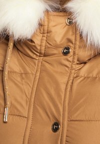 Brown puffer jacket with a fur-lined collar, featuring gold-accented drawstrings and gold buttons along the front. Soft, quilted texture.