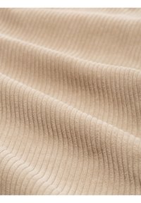 Tissu côtelé beige avec des côtes verticales douces et uniformément espacées créant de doux plis et des détails de texture.