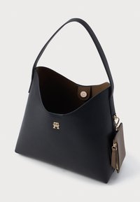 Sort læderhåndtaske med en glat tekstur, buet design, guld logo-accent og aftagelig lille pung. Indvendigt er den brun.