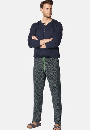 Navy long-sleeve shirt with green accents, paired with patterned pajama pants featuring polka dots and an adjustable green drawstring.