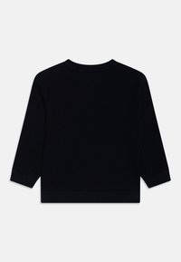 Črna rebrasta top s dolgimi rokavi, ki ima okroglo ovratnico, subtilno teksturo in prilegajoče manšete. Zadaj se ponaša z enostavno, minimalistično zasnovo.