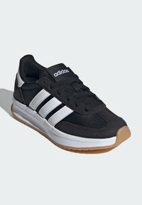 Čierna športová obuv s bielymi pruhmi adidas, textilný zvršok, gumová podrážka, polstrovaný golier a šnurovanie. Obsahuje hnedú podrážku.