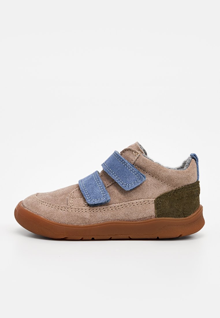 Zapato de ante marrón con correas de Velcro azul, acentos verdes en el talón y suela de goma marrón texturizada. Diseño bajo, con forro interior de fleece.